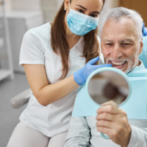 Elderly,Man,And,His,Young,Female,Dentist,Smiling,While,Looking